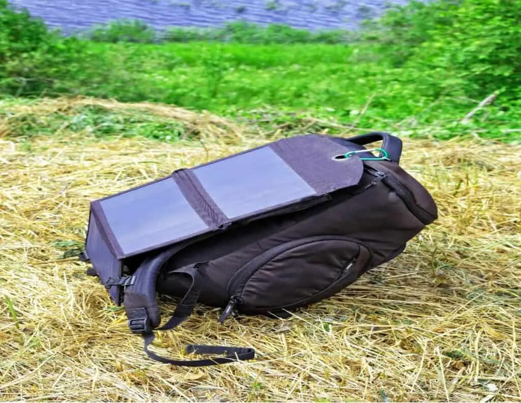 Solar backpack on grass near lake.