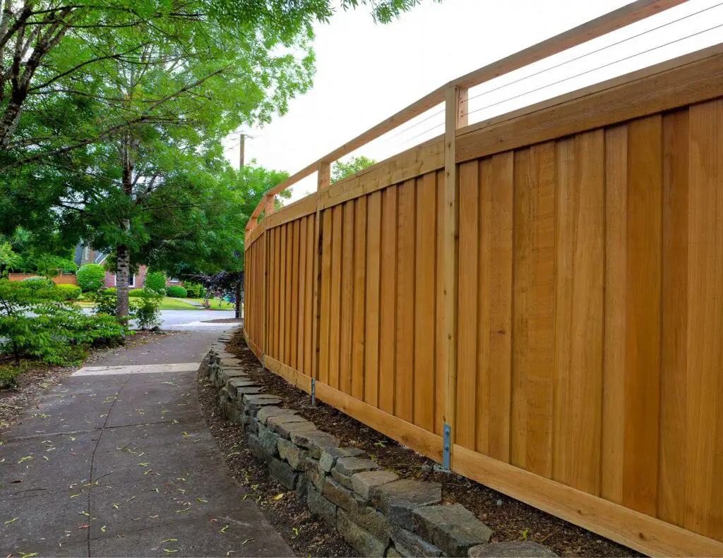 Fence separating a yard from a public walking path.